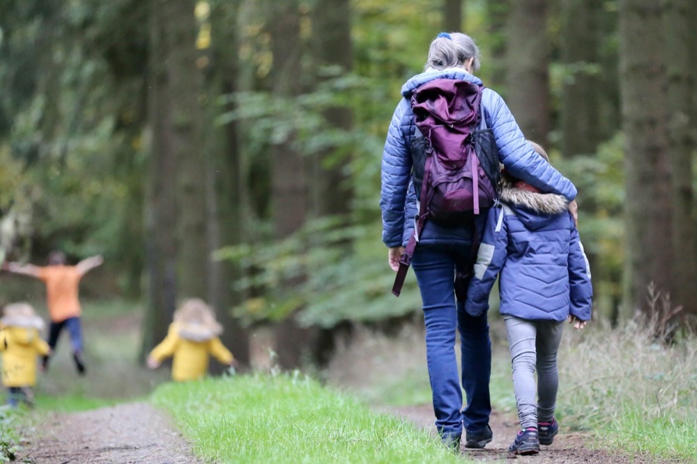 A parent walking a forest path while the kids run ahead
