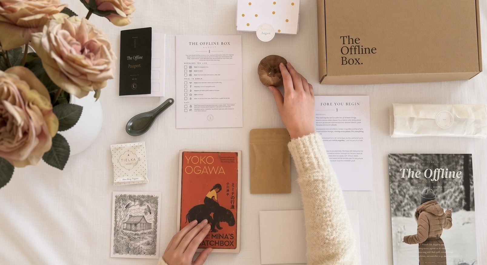 An Offline Box laid out on a white table — book, magazine, tea, seeds and the passport